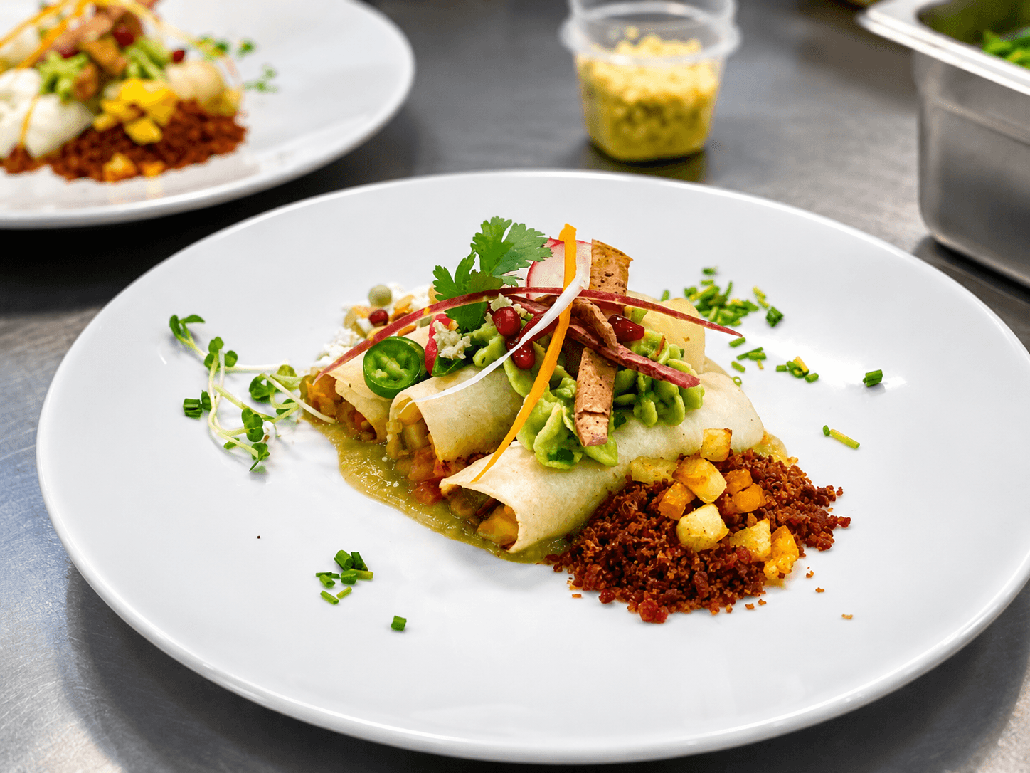 A plate of enchiladas topped with avocado, jalapeños, and garnishes, served with diced potatoes and crumbled chorizo.
