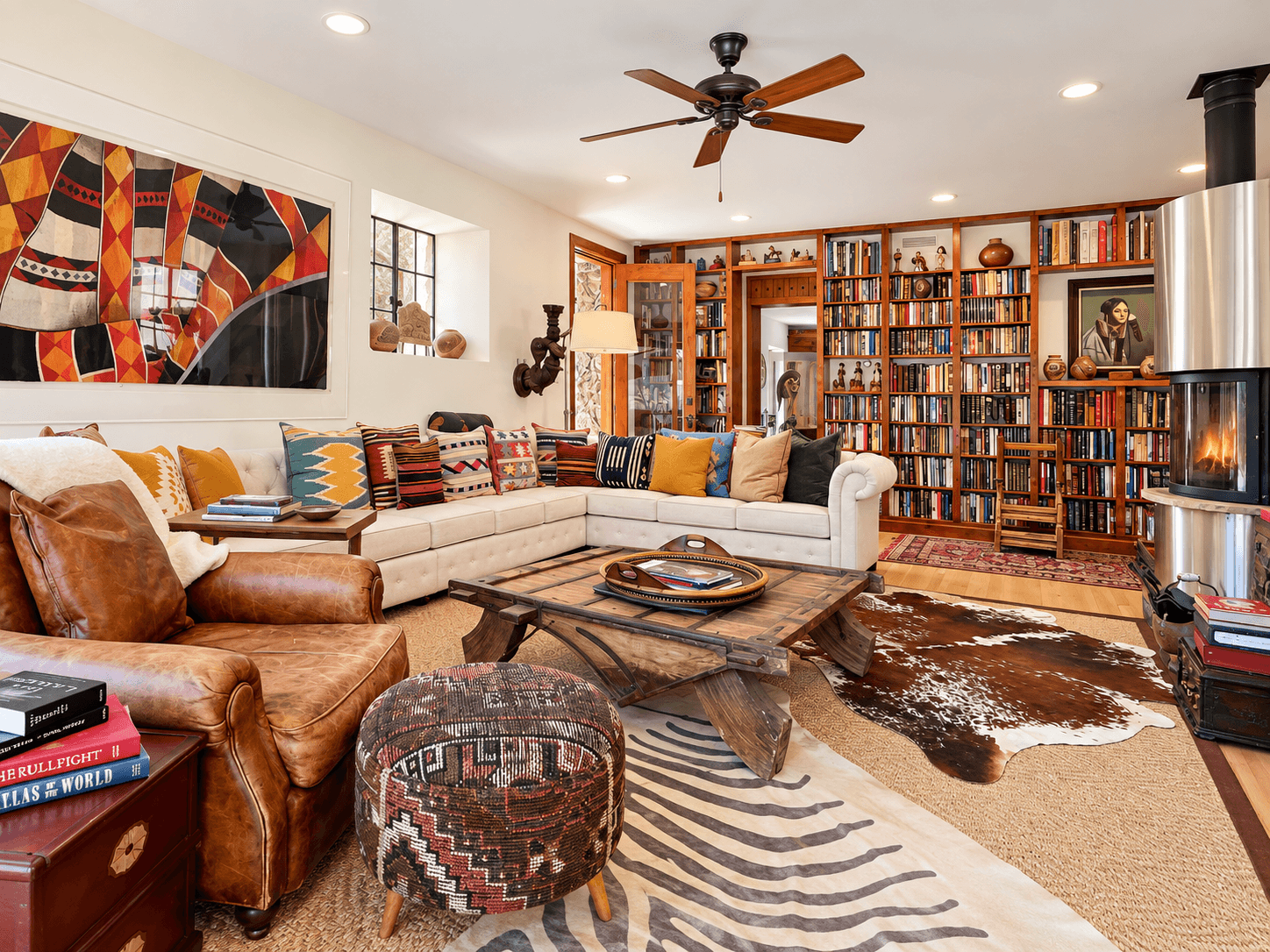 Cozy living room featuring a sectional sofa, a wooden coffee table, a bookcase, and a warm fireplace.