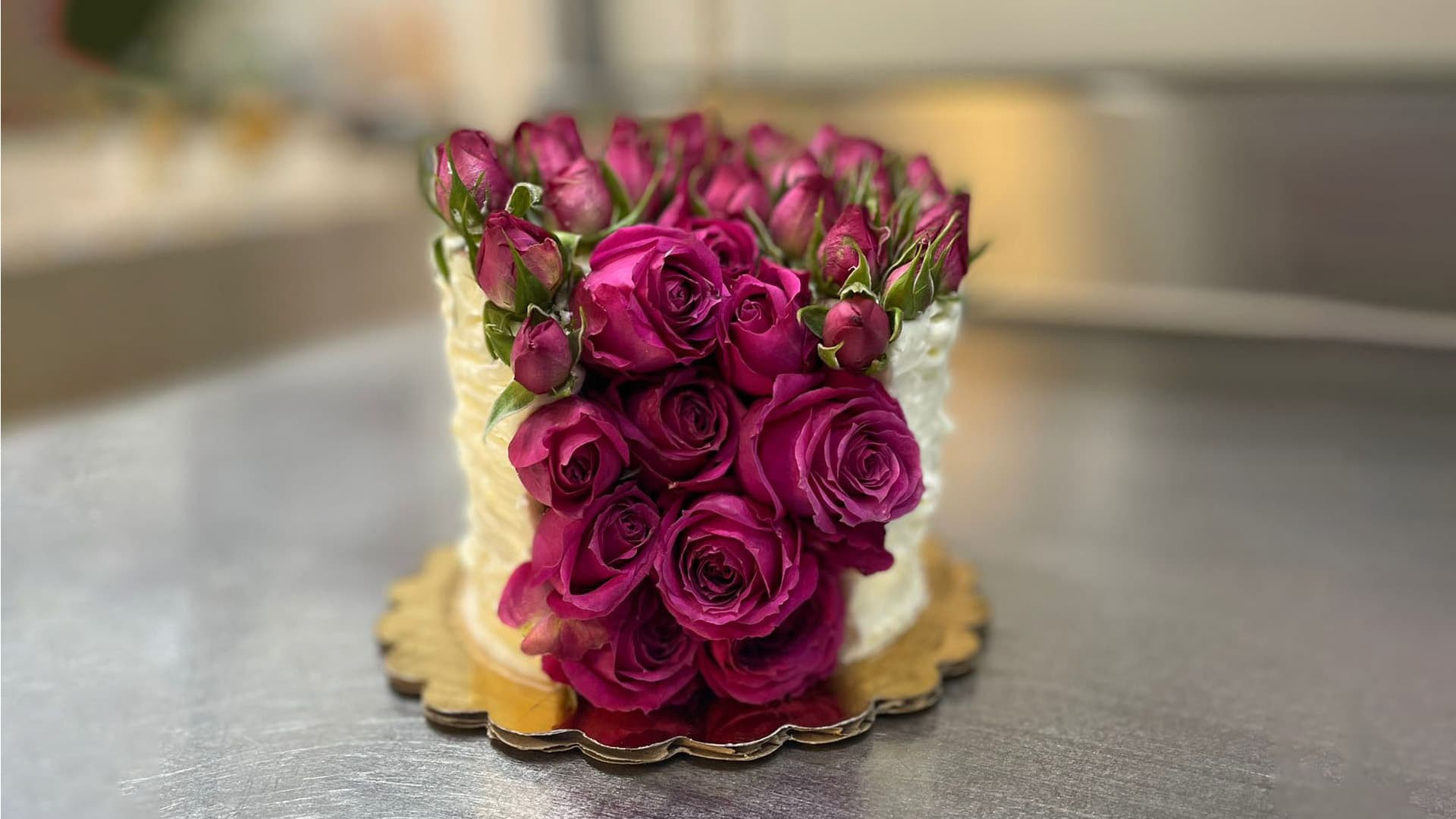 A beautifully decorated cake topped with vibrant pink roses.