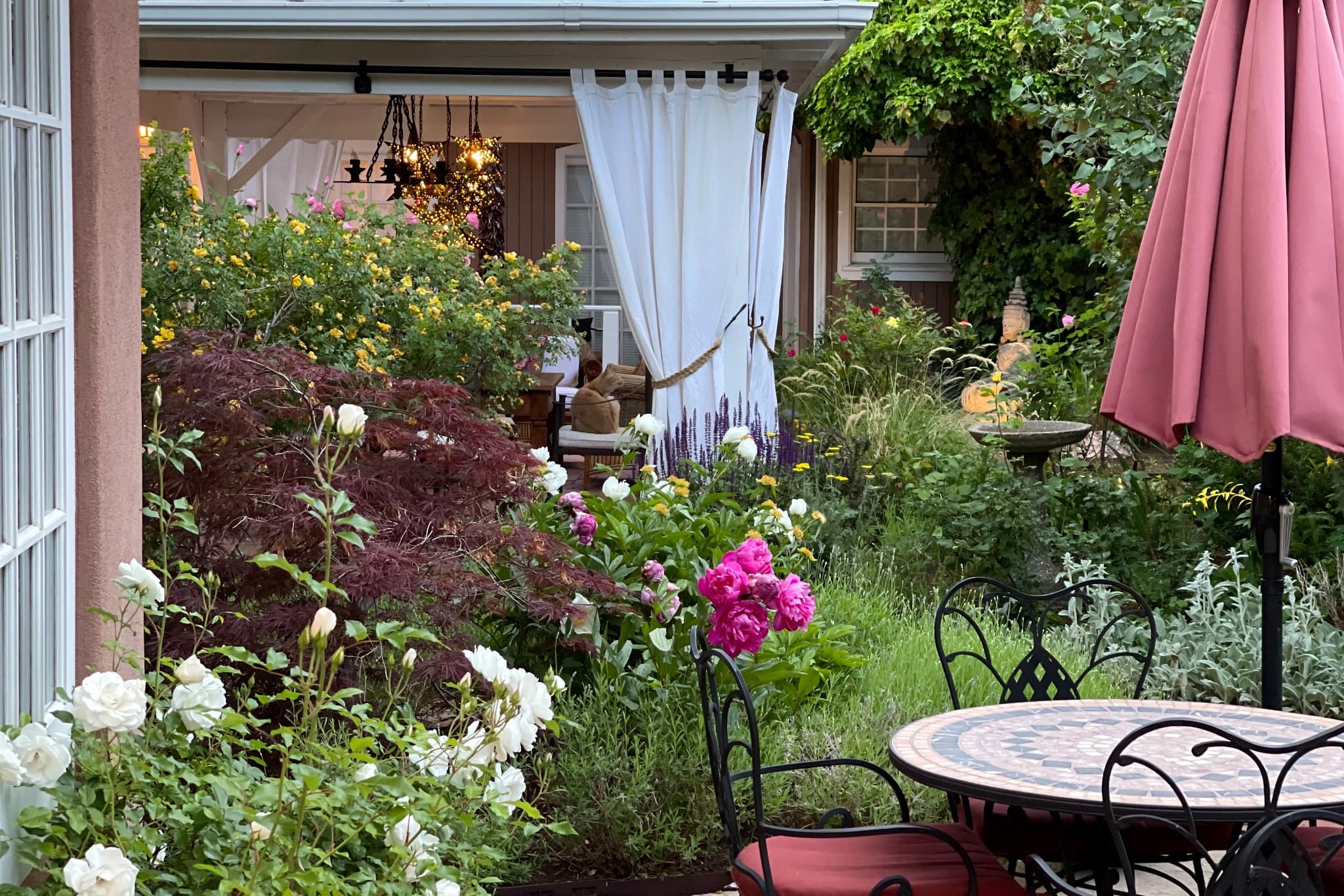 A lush garden filled with colorful flowers and a seating area, leading to a cozy indoor space.
