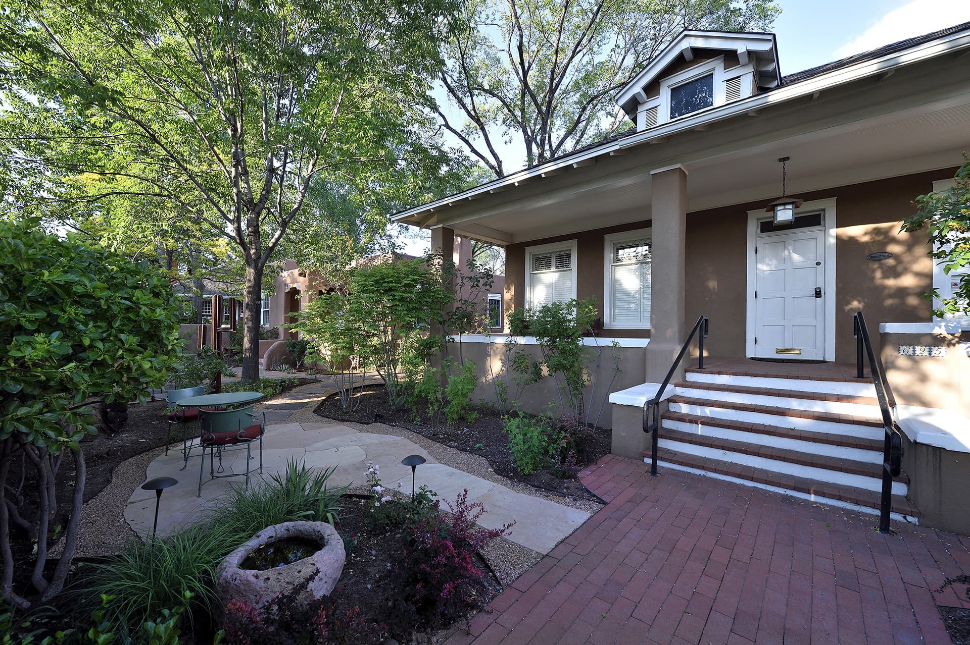 Front view of a house with a landscaped walkway and seating area.