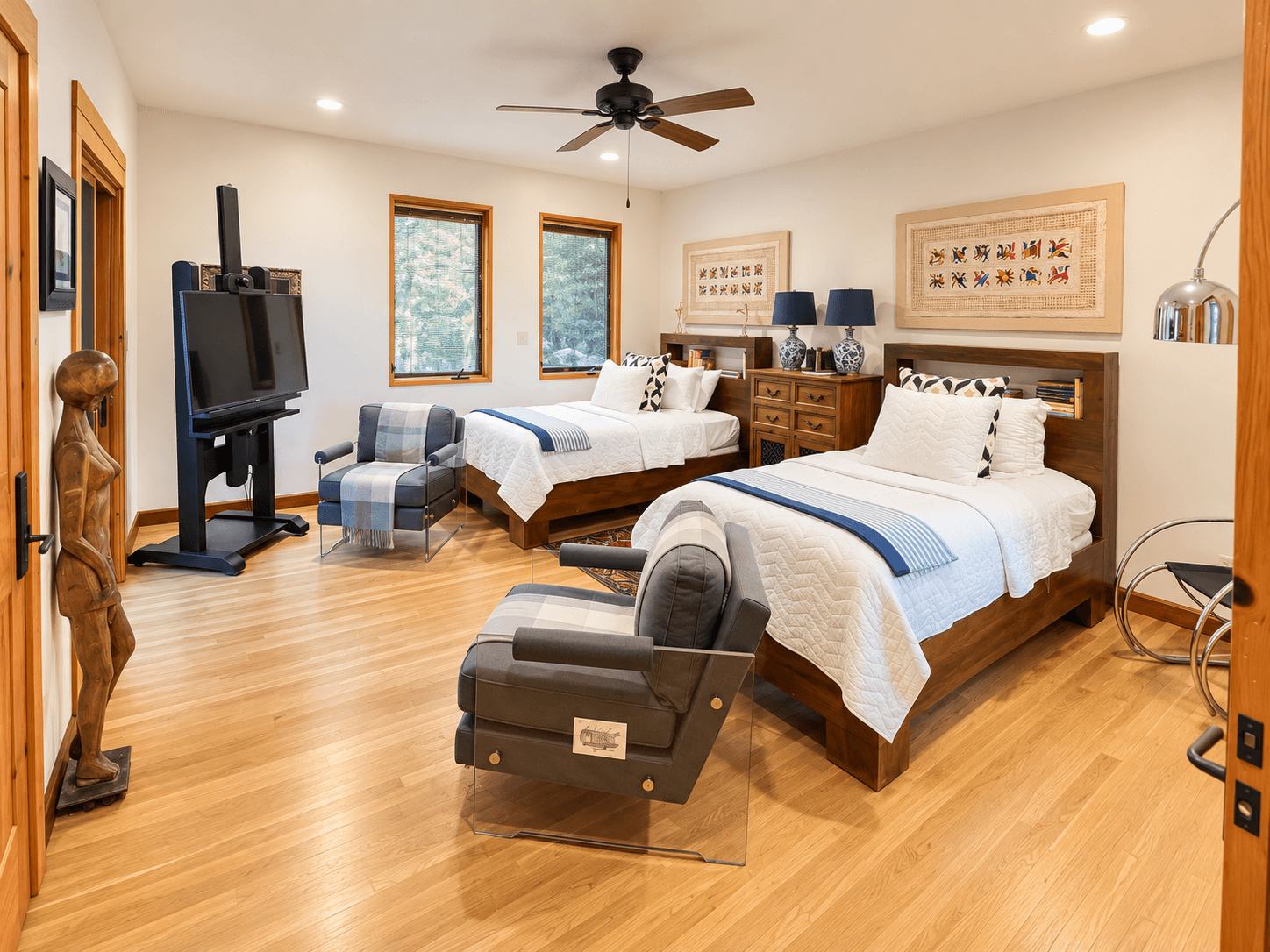 A spacious bedroom featuring two twin beds, modern furniture, and large windows with natural light.