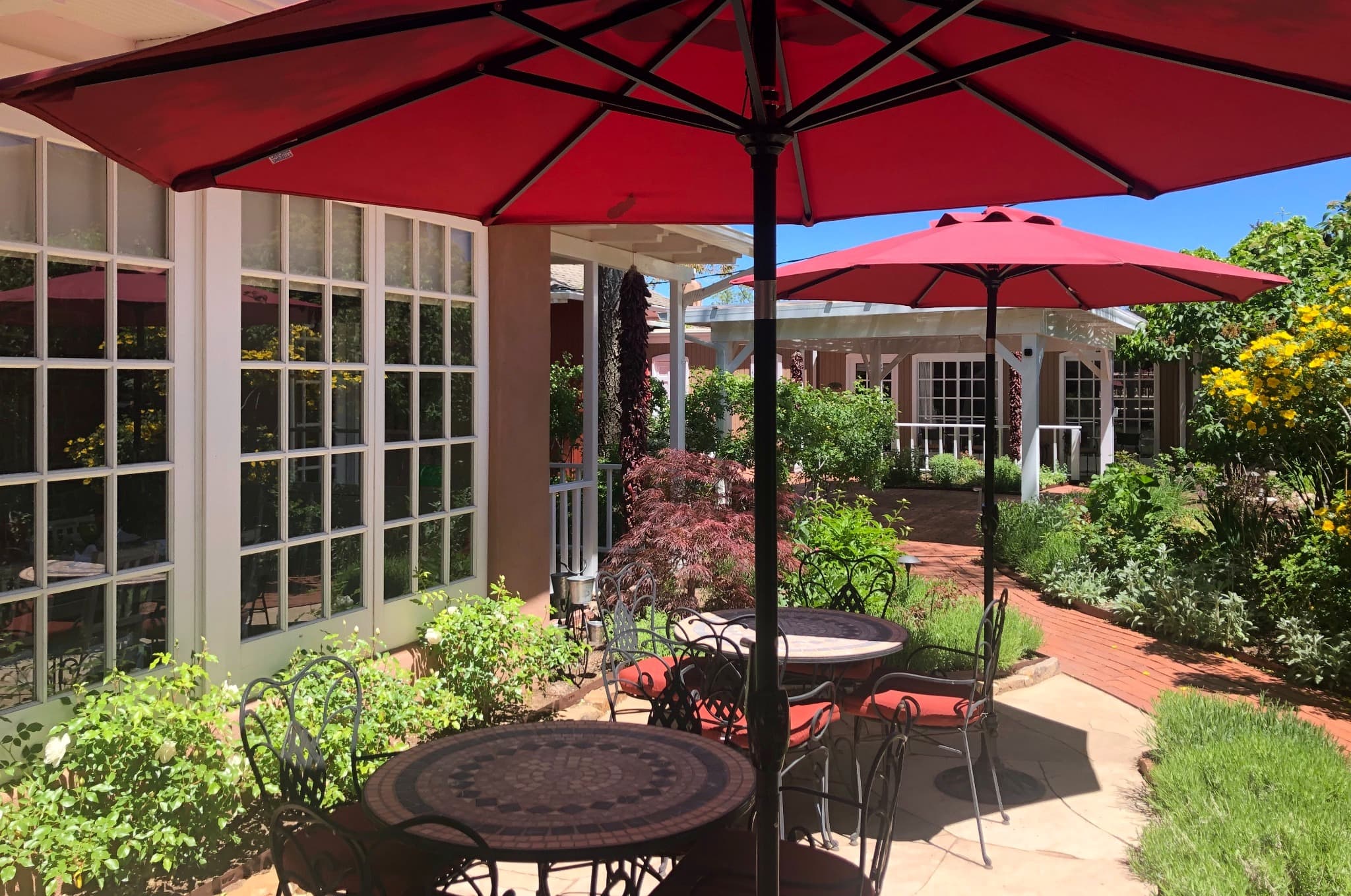 Outdoor seating area with red umbrellas and lush greenery.