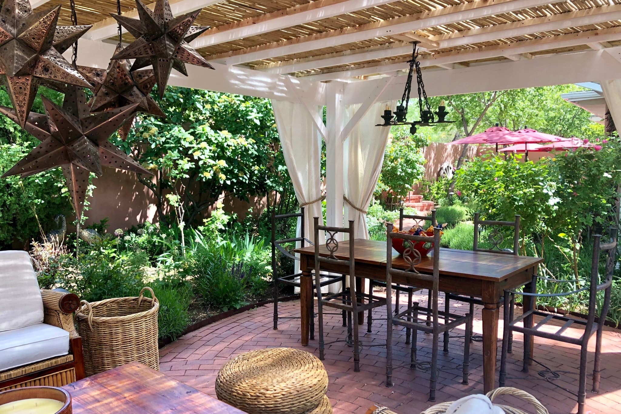 A serene outdoor dining area with a wooden table and chairs, surrounded by lush greenery and decorative star-shaped accents.