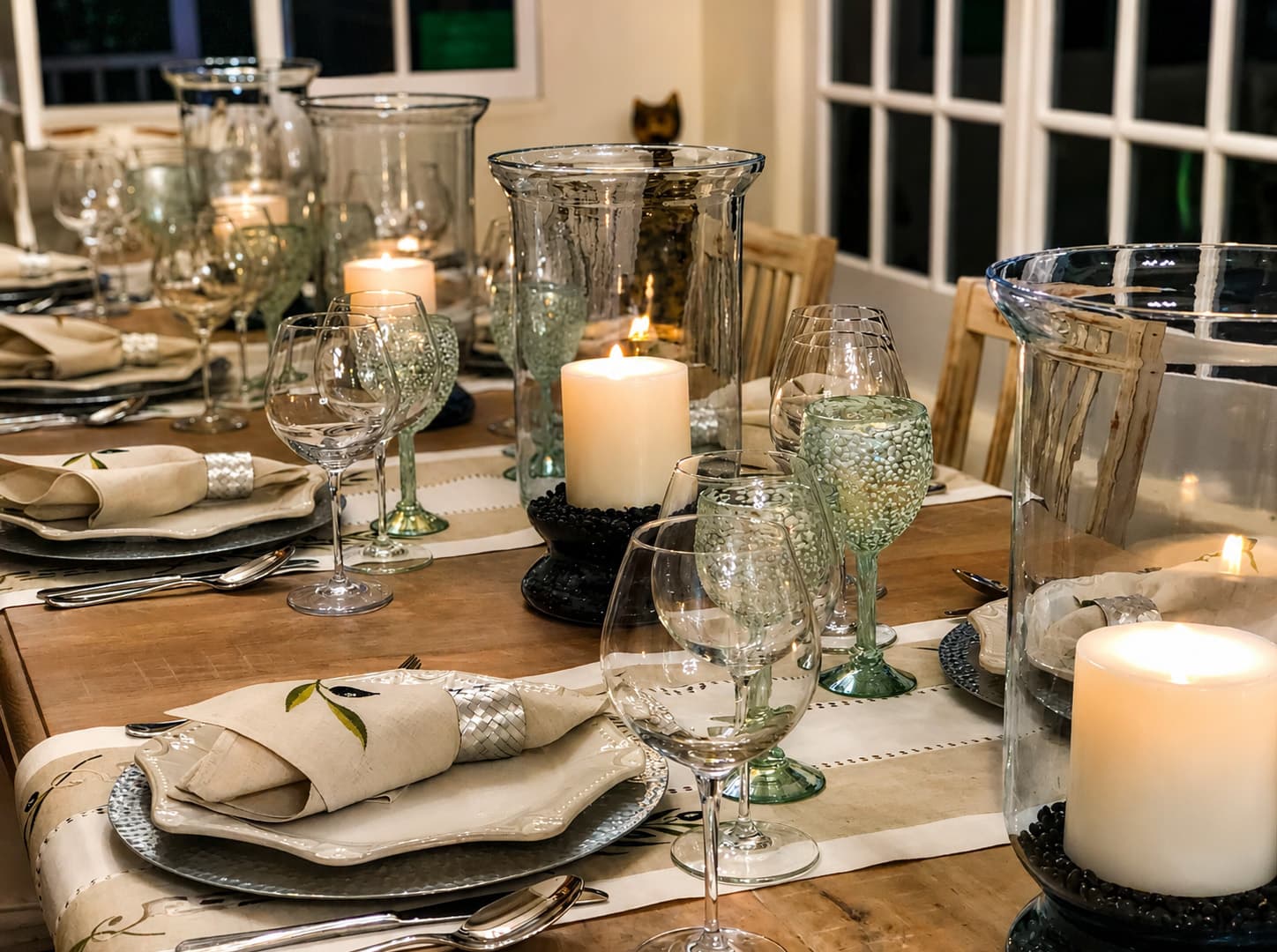 A beautifully set dining table with elegant glassware, napkins, and candles.