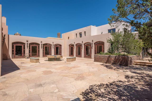 A sunny courtyard surrounded by adobe-style buildings and landscaped greenery.