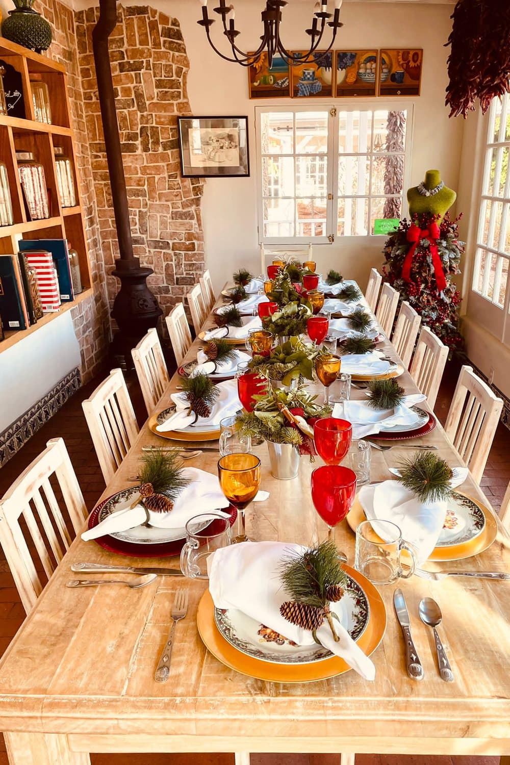 A beautifully set dining table adorned with festive decorations, including pinecones and greenery, in a warm, inviting interior.