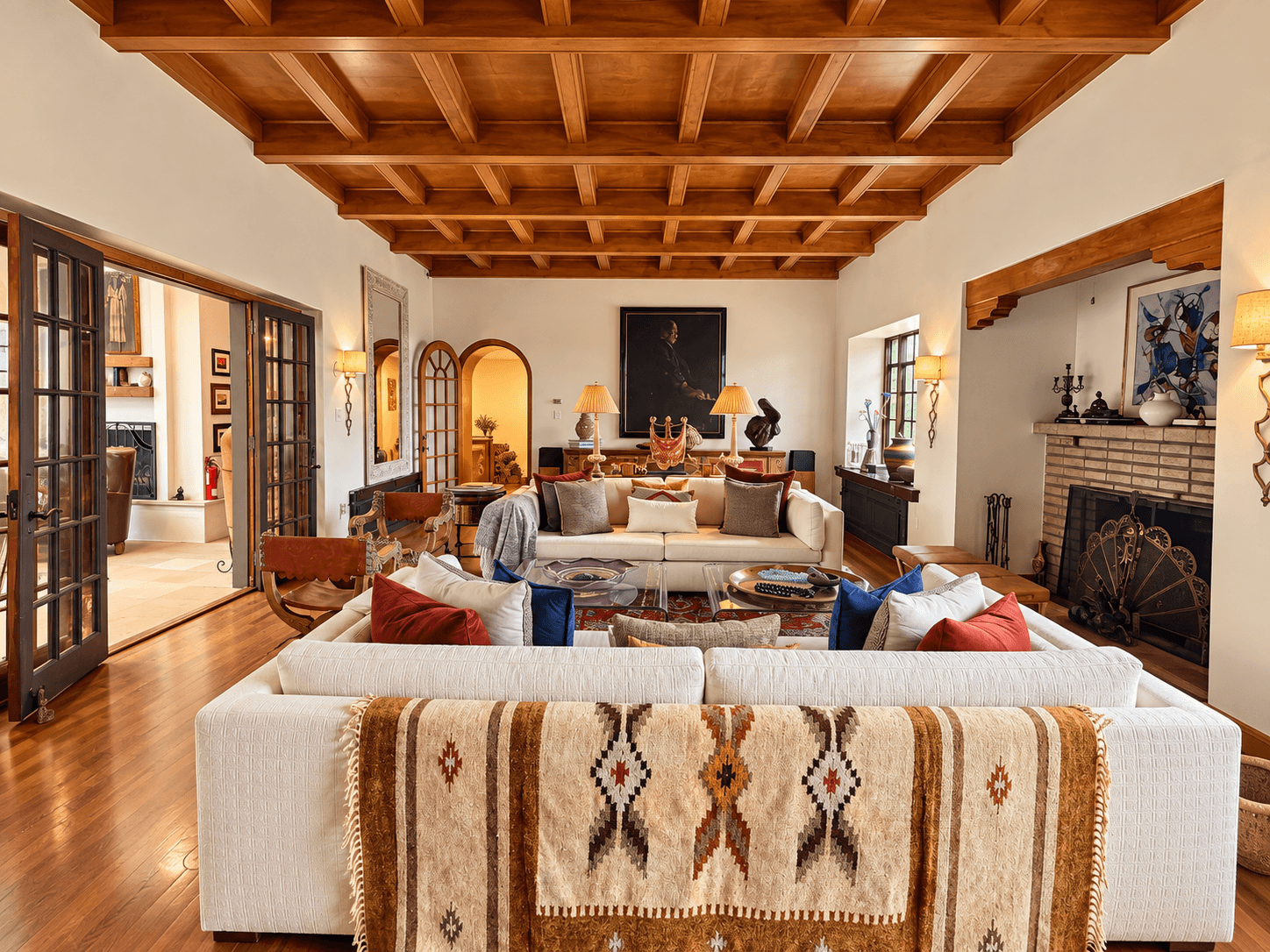 A cozy living room featuring a beige sectional sofa, wooden beams, and artistic decor.