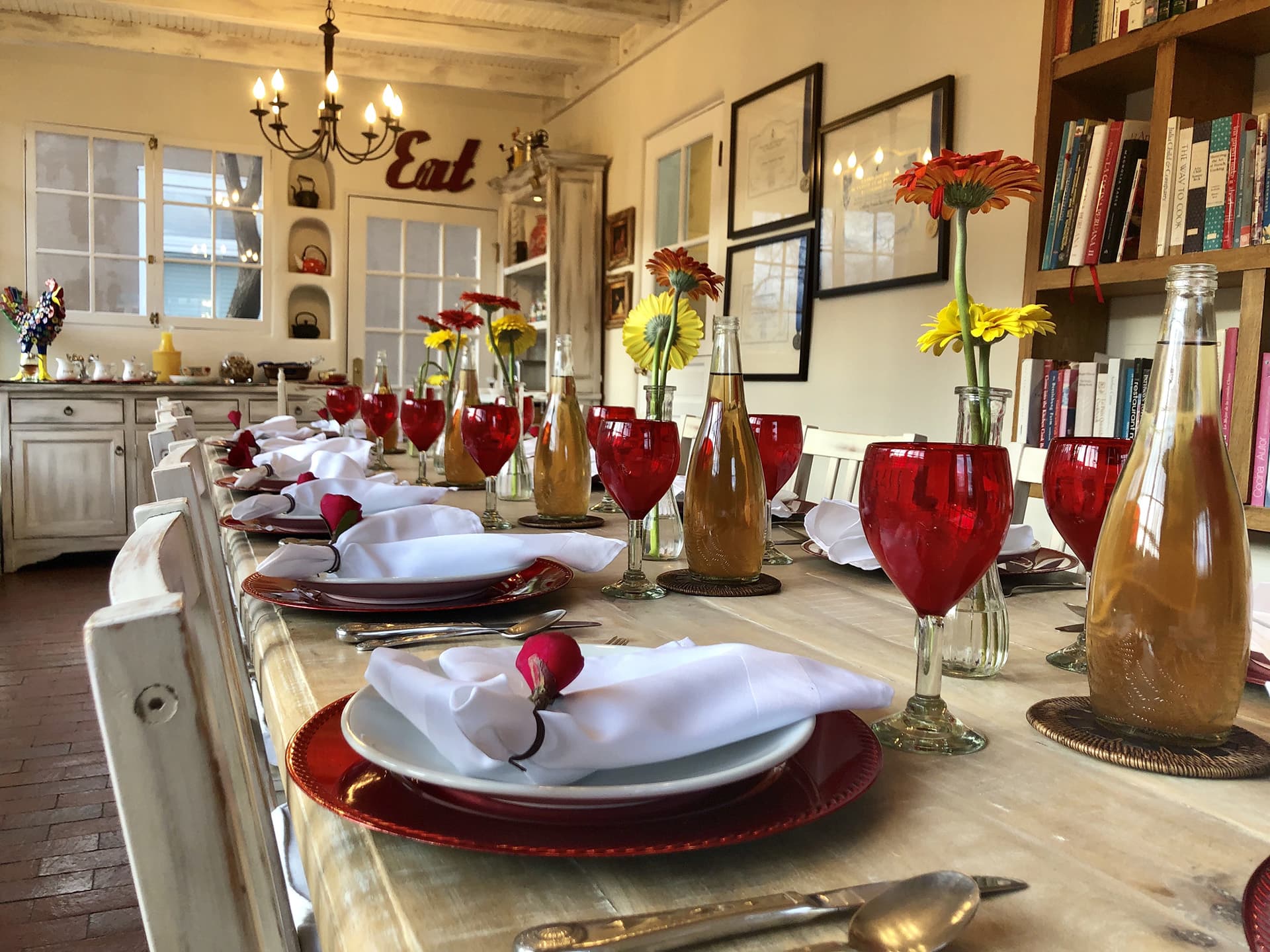 A beautifully set dining table adorned with red glasses, flowers, and elegant tableware.