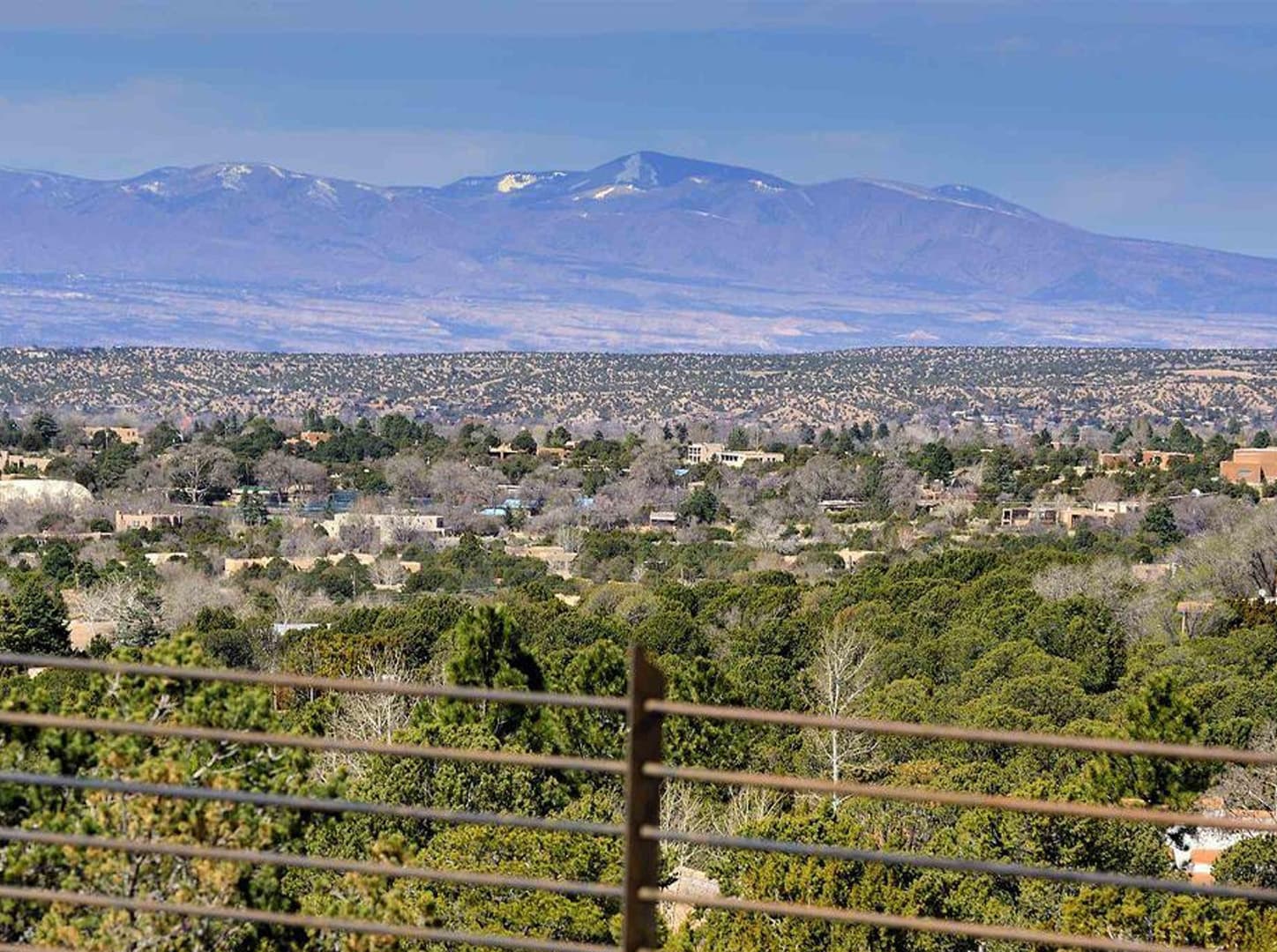 Panoramic view of a valley with scattered buildings and distant mountains under a clear sky.
