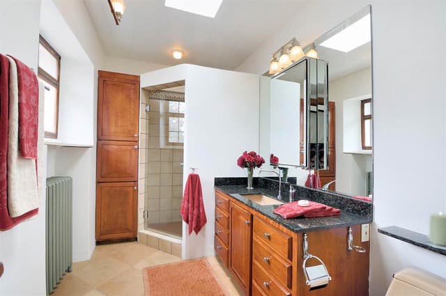 Bright bathroom featuring a wooden vanity, large mirror, and a glass shower.