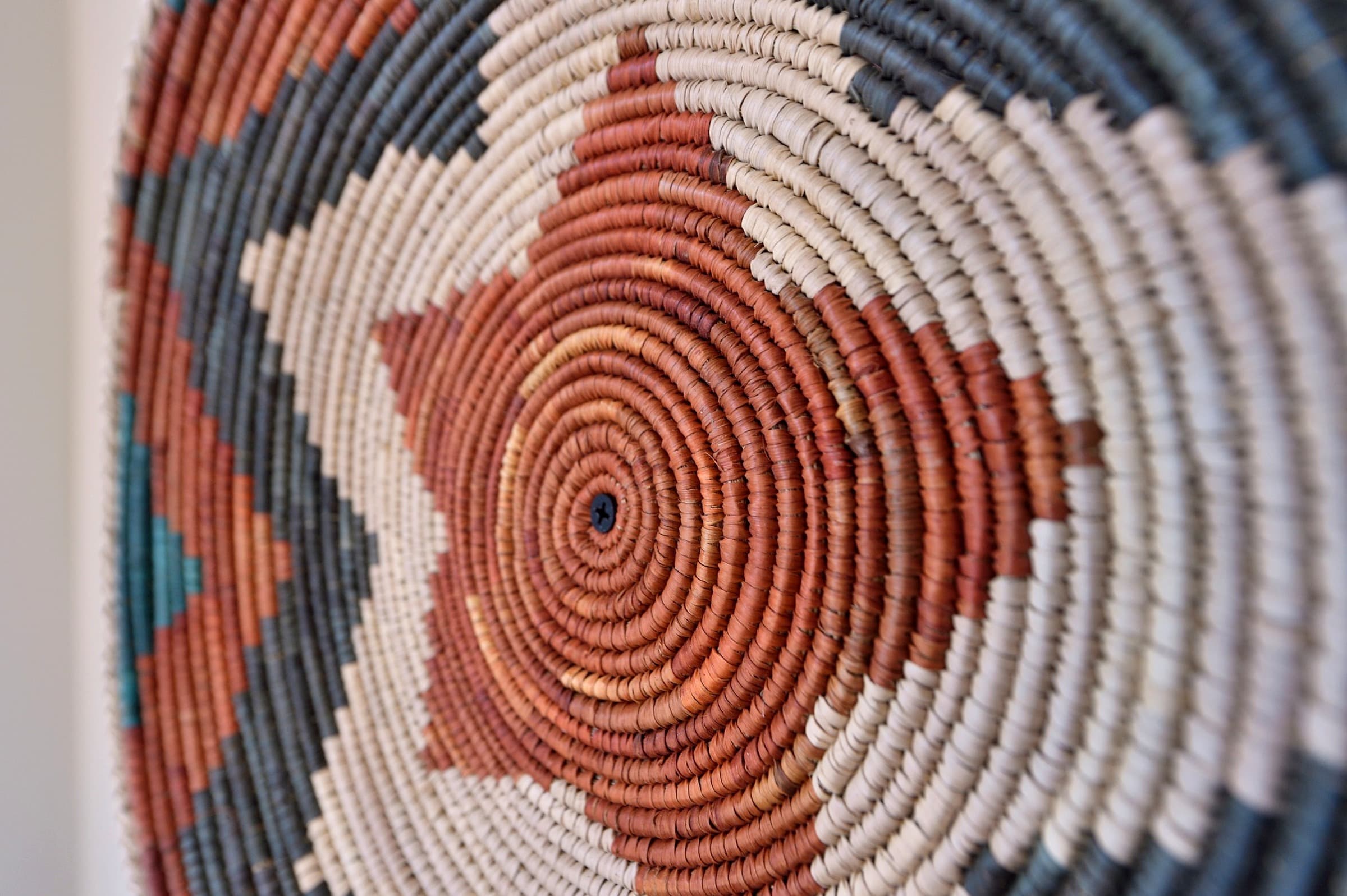 Close-up of a circular woven basket with earthy tones and geometric patterns.