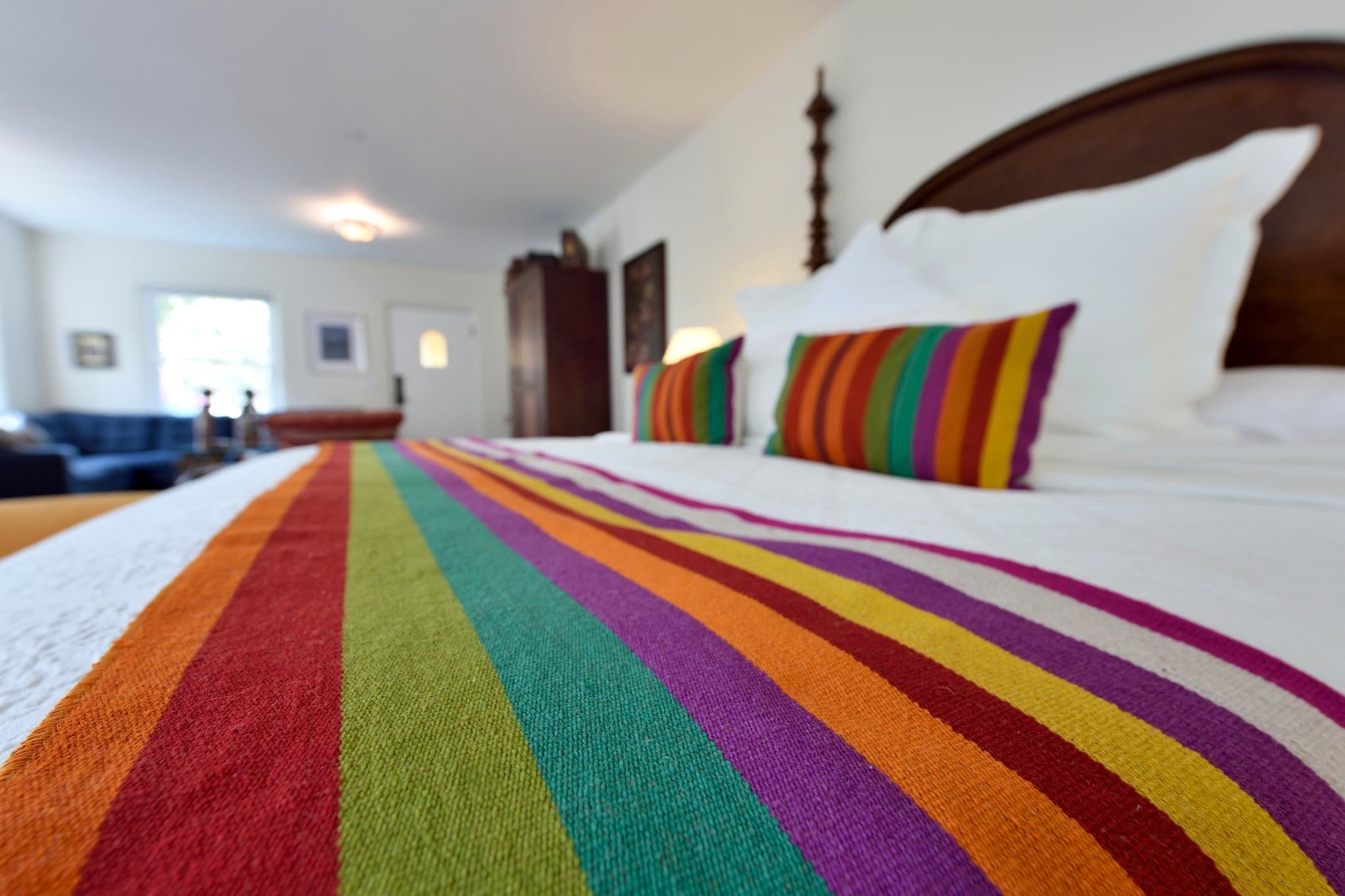 A colorful striped blanket drapes over a neatly made bed in a bright, inviting room.