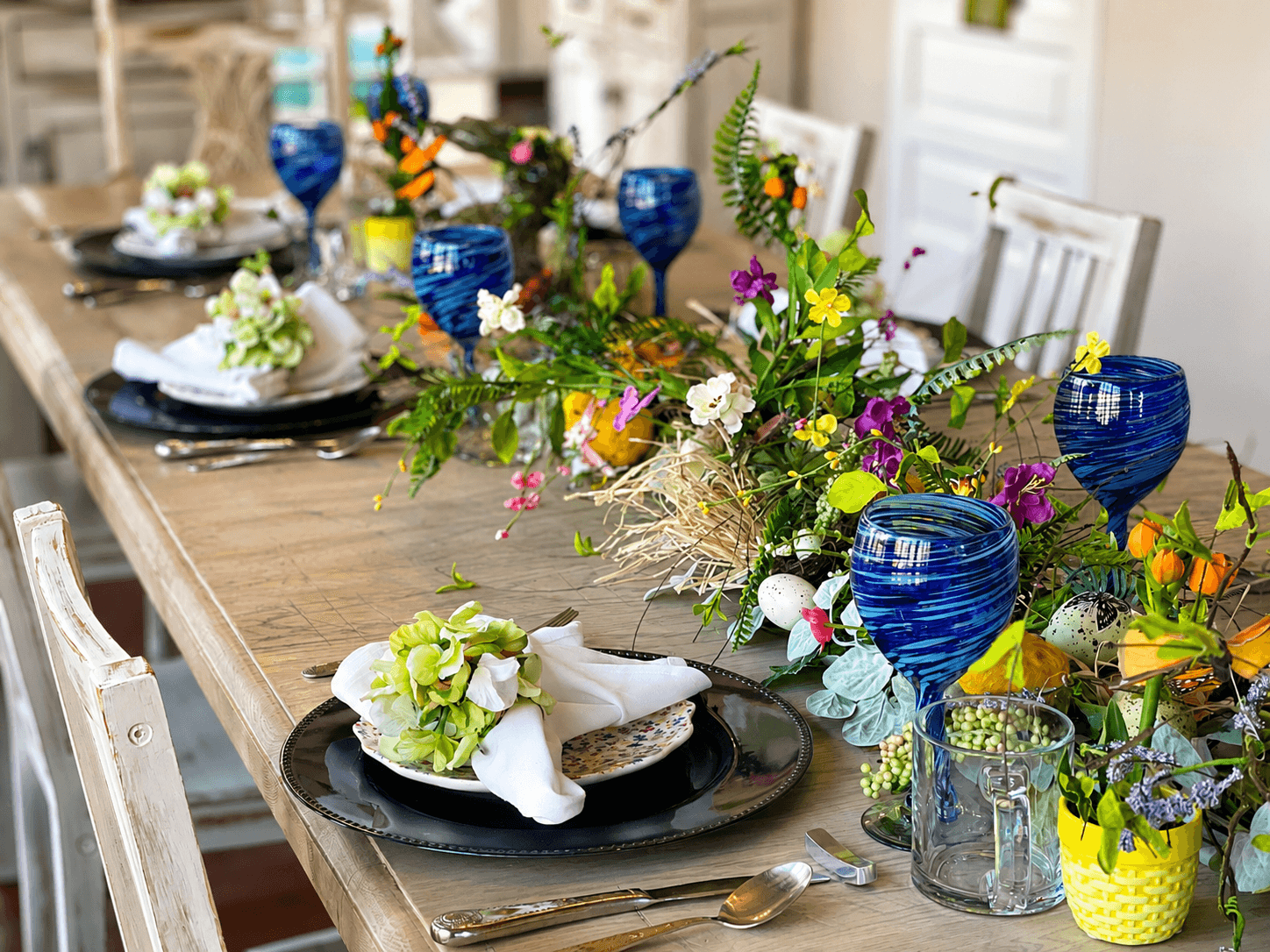 A beautifully set dining table adorned with vibrant floral arrangements and blue glassware.