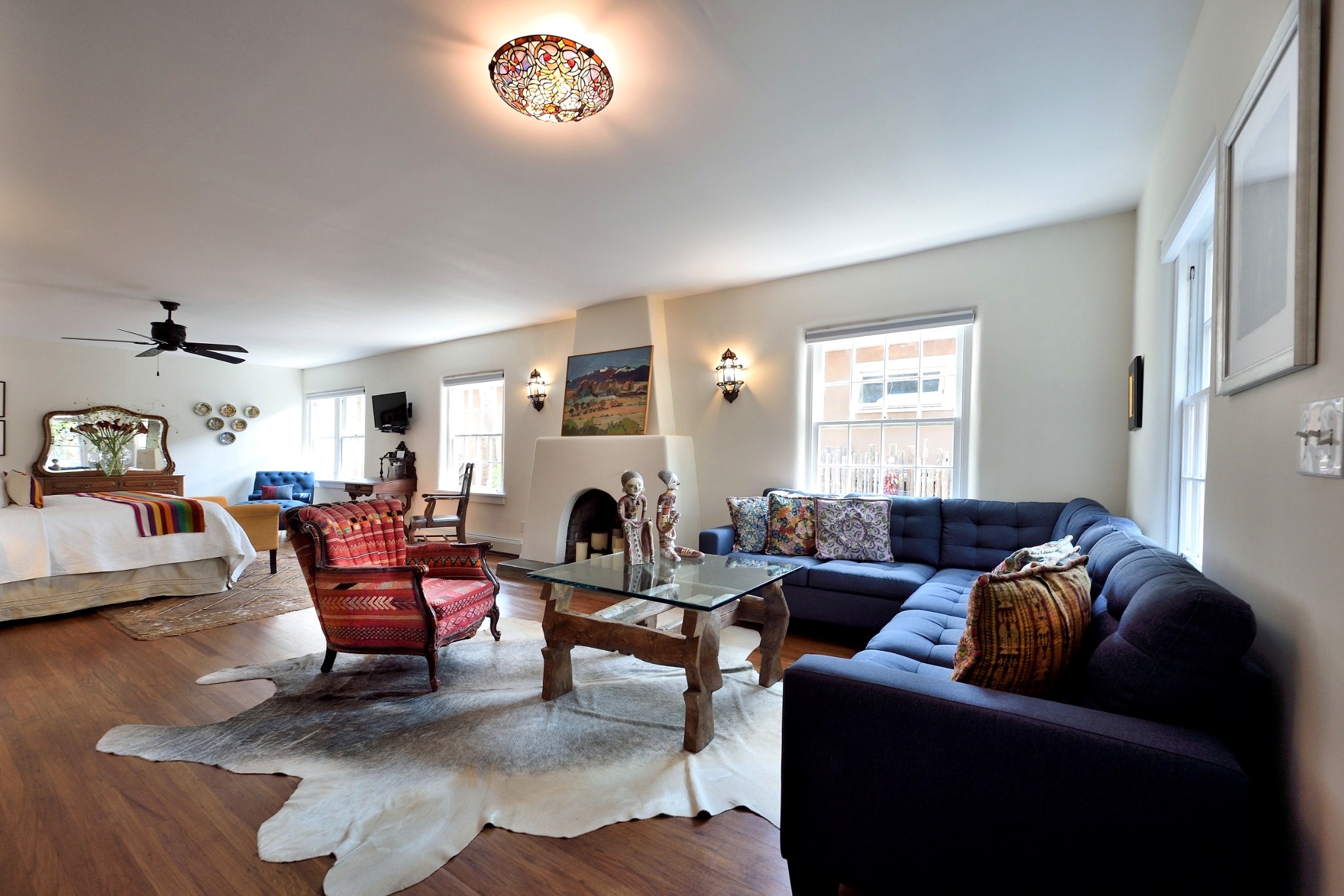 A cozy living space featuring a blue sofa, red accent chairs, a coffee table, and decorative elements in warm tones.