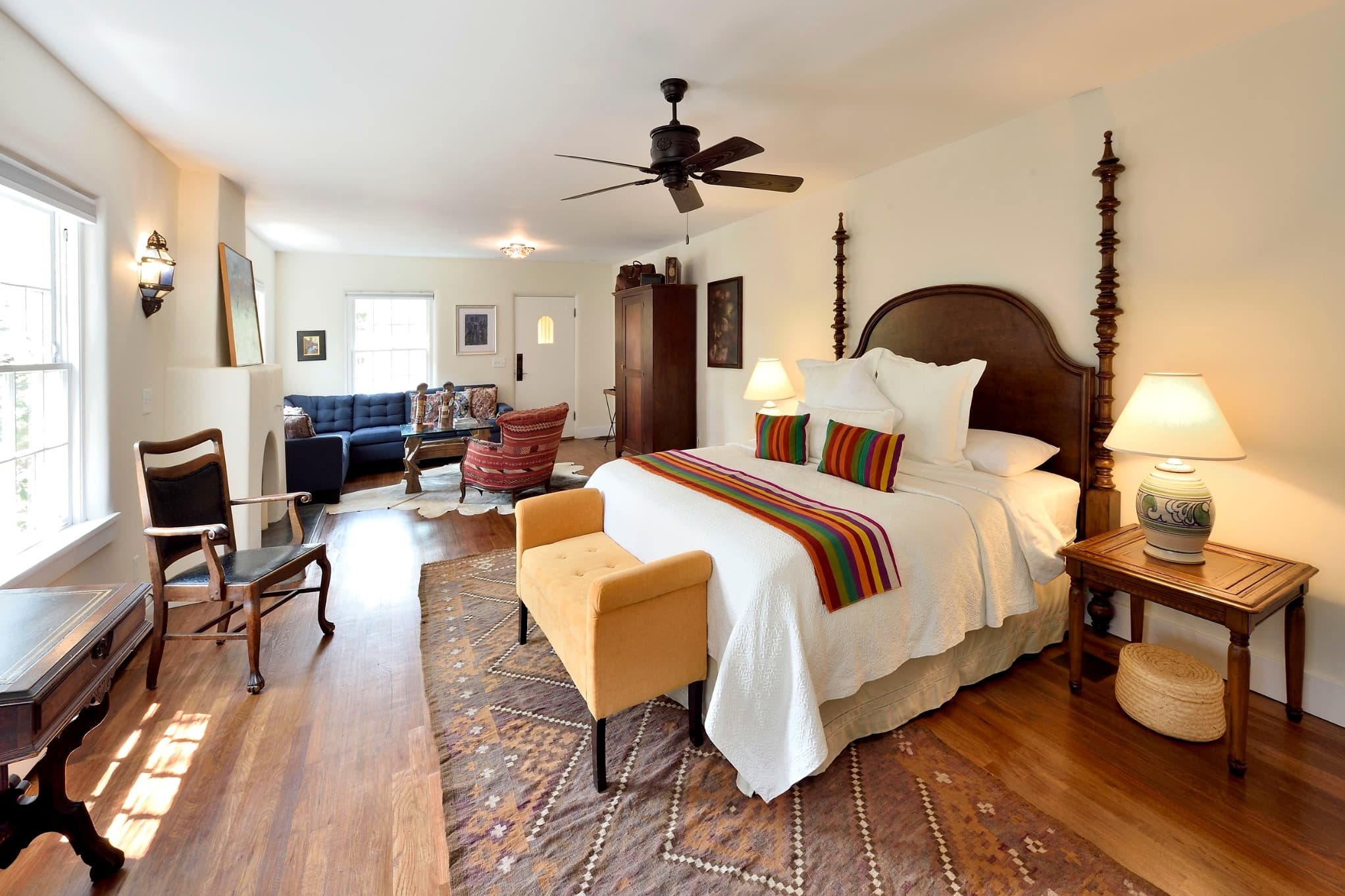 A cozy bedroom featuring a large bed, colorful throw pillows, and a small sitting area with a sofa.