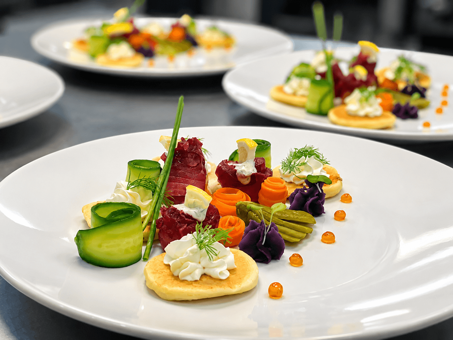 A beautifully arranged plate of colorful vegetables and garnishes on a white dish, featuring various textures and elements.