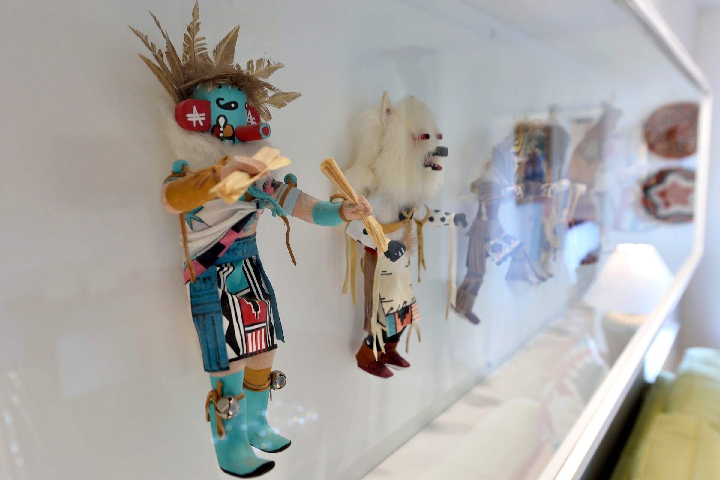 A row of colorful, traditional dolls displayed against a white background.