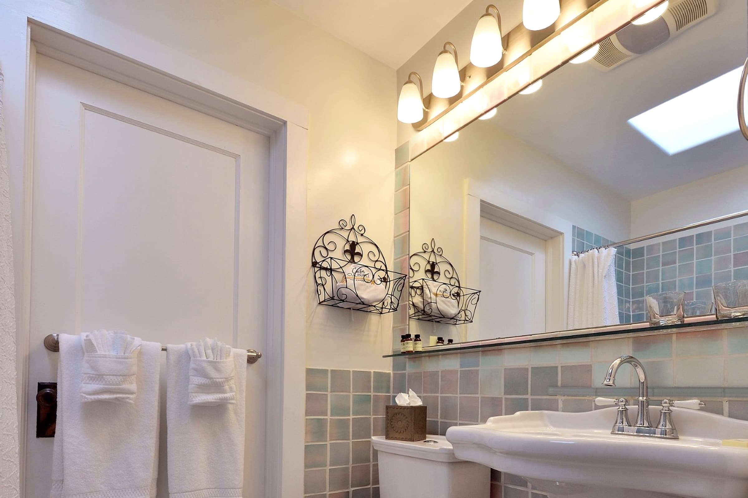 A bright and modern bathroom featuring a sink, decorative wall shelves, and fluffy white towels.
