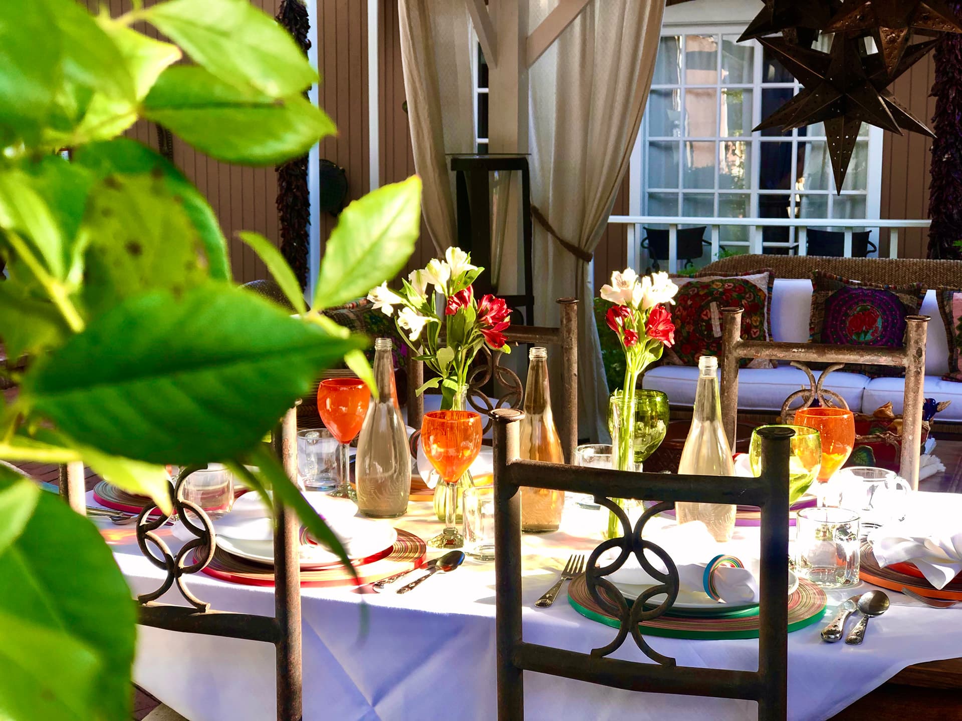 A beautifully set outdoor dining table adorned with flowers and colorful glasses.