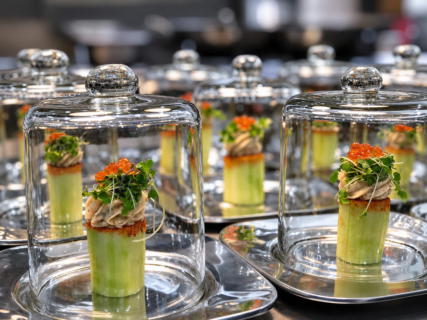 Elegant appetizers served under glass cloches, featuring cucumber, garnishes, and toppings.