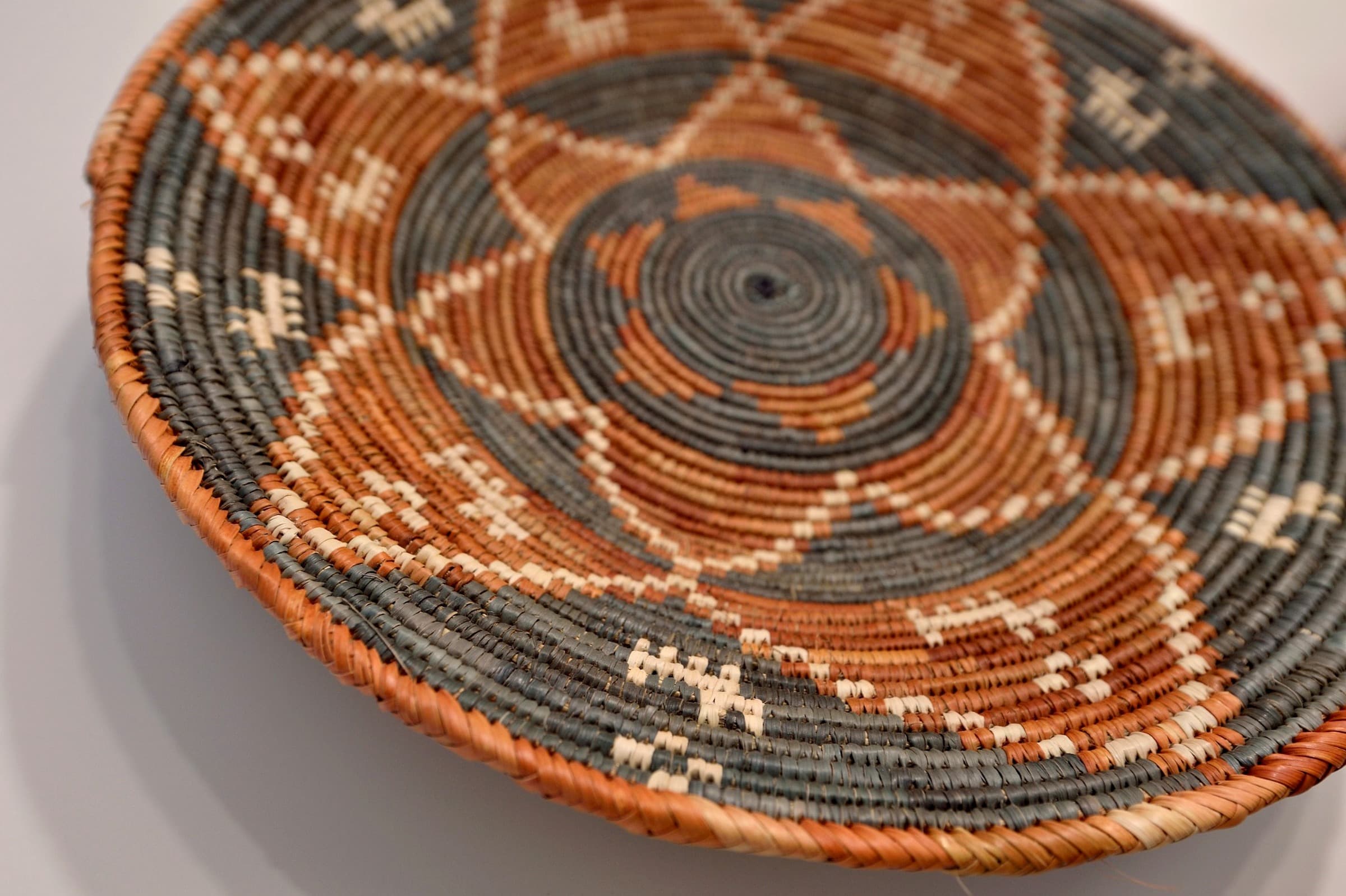 A decorative woven basket showcasing intricate geometric patterns in earthy tones.